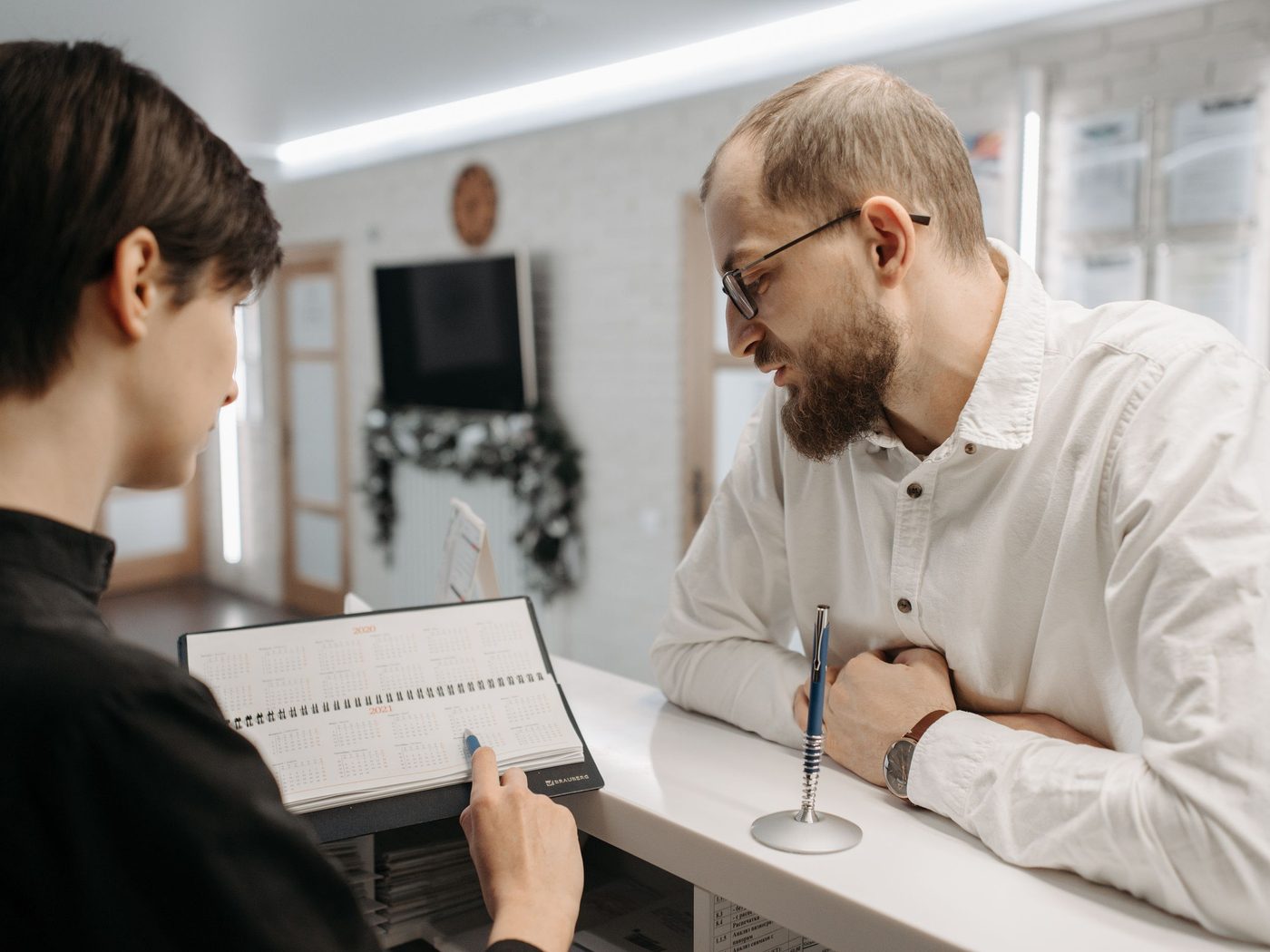 A client completing paperwork with a receptionist at a clinic desk